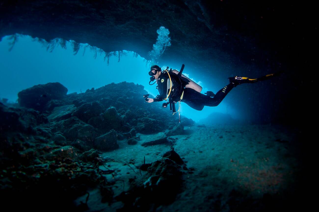 Diver exploring an underwater cave and reef near Bequia, St. Vincent and the Grenadines